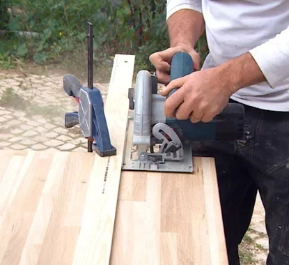 senhor a utilizar uma serra vertical para cortar o painel de madeira à medida pretendida