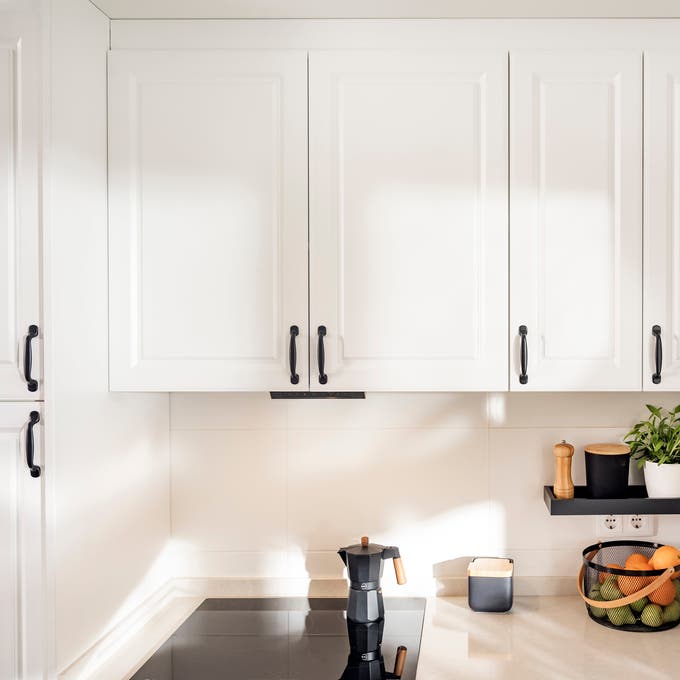 Cocina blanca con tiradores negros.