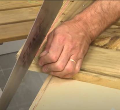 Pessoa a cortar uma placa de deck com um serrote