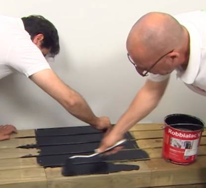Dois homens a pintar as placas de deck com tinta para madeira preta