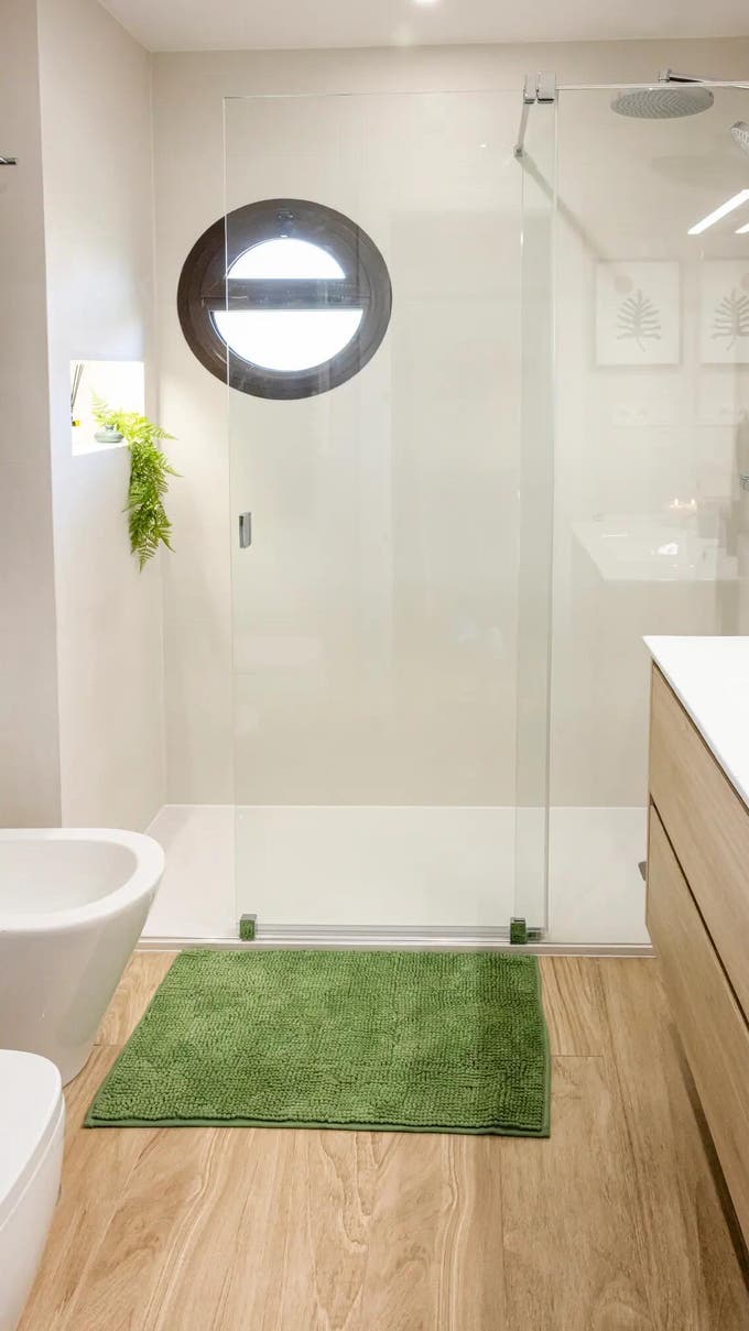 Baño con alfombra de baño verde. 