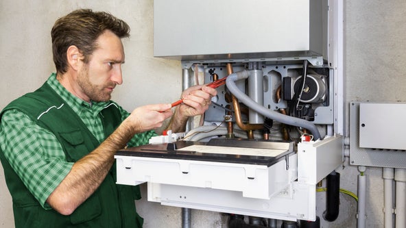 grafika - monter instaluje kocioł grzewczy