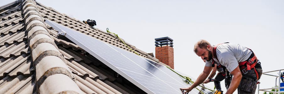 photo de 2 personnes en train d'installer des panneaux solaires sur le toit d'une maison