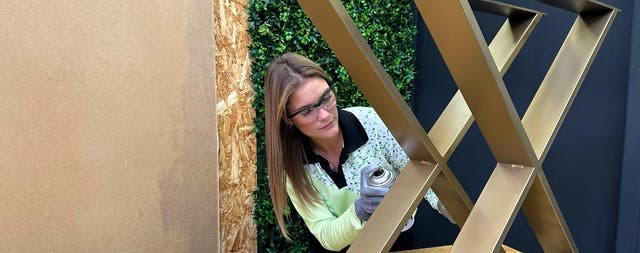 colaboradora a pintar os pés metálicos de uma mesa