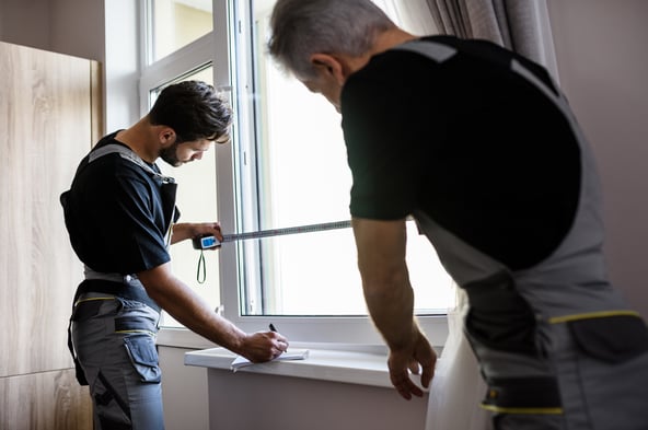 montażyści mierzący pomieszczenie