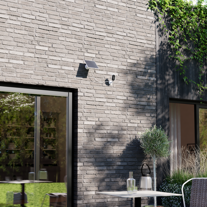 Caméra solaire Lexman sur un mur à l'extérieur d'une maison observant le jardin