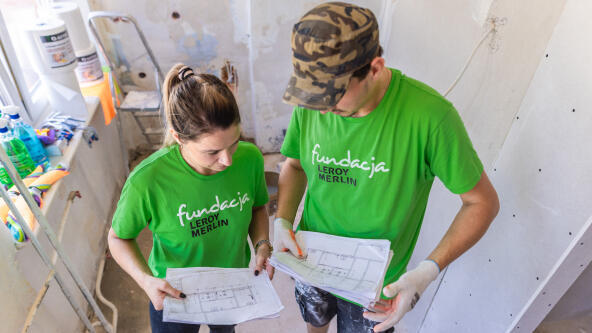 zdjęcie dwóch osób trzymających w rękach plany remontowanych pomieszczeń