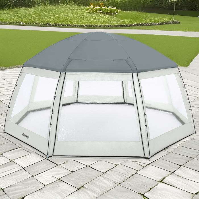Pawilon / namiot Bestway do basenów o wymiarach 600x600x295 cm, w kolorze szaro-białym, ustawiony na brukowanym podłożu, z kopułowym dachem i siatkowanymi ścianami zapewniającymi wentylację i ochronę przed owadami, w tle widoczny trawnik i rabata z roślinami.