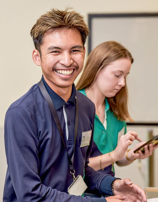 jeuen collaborateur souriant avec une collègue en arrière plan