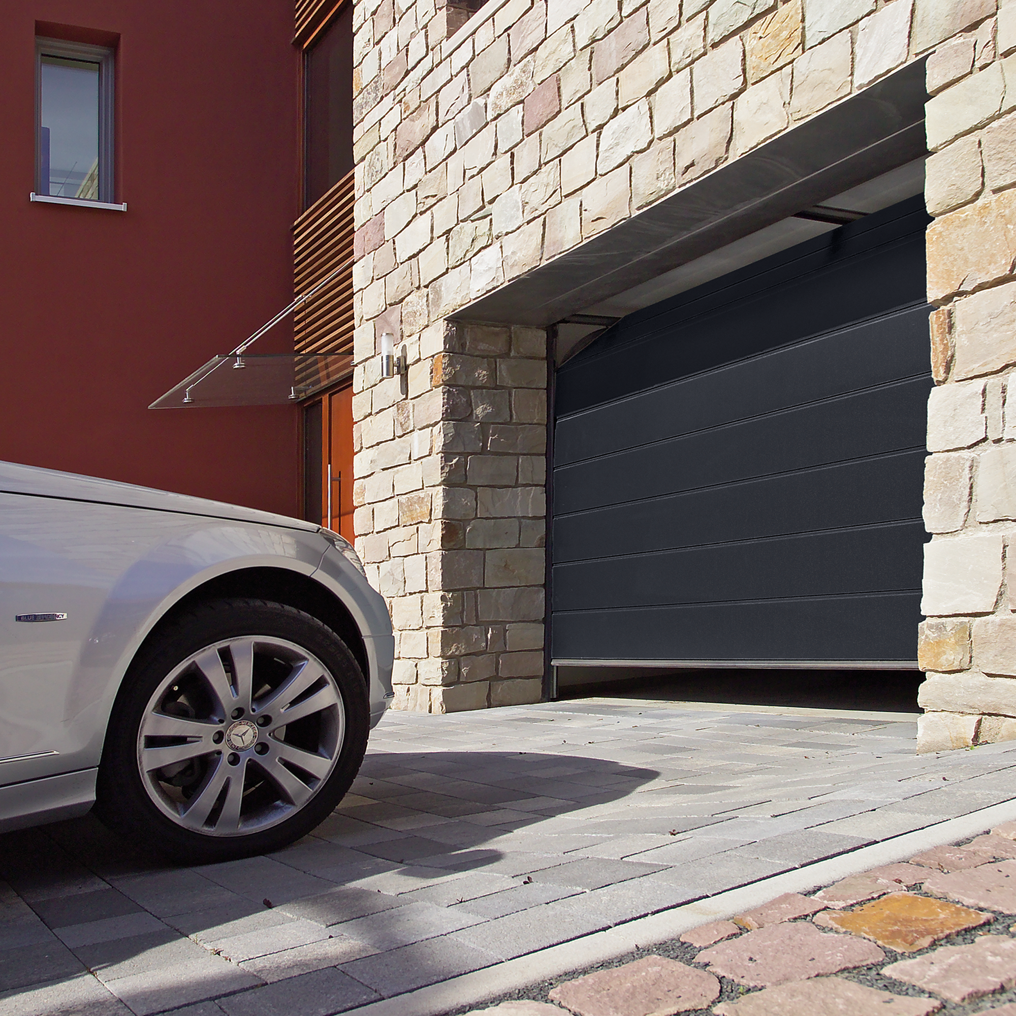 Brama segmentowa Isomatic w garażu z kamienną elewacją.