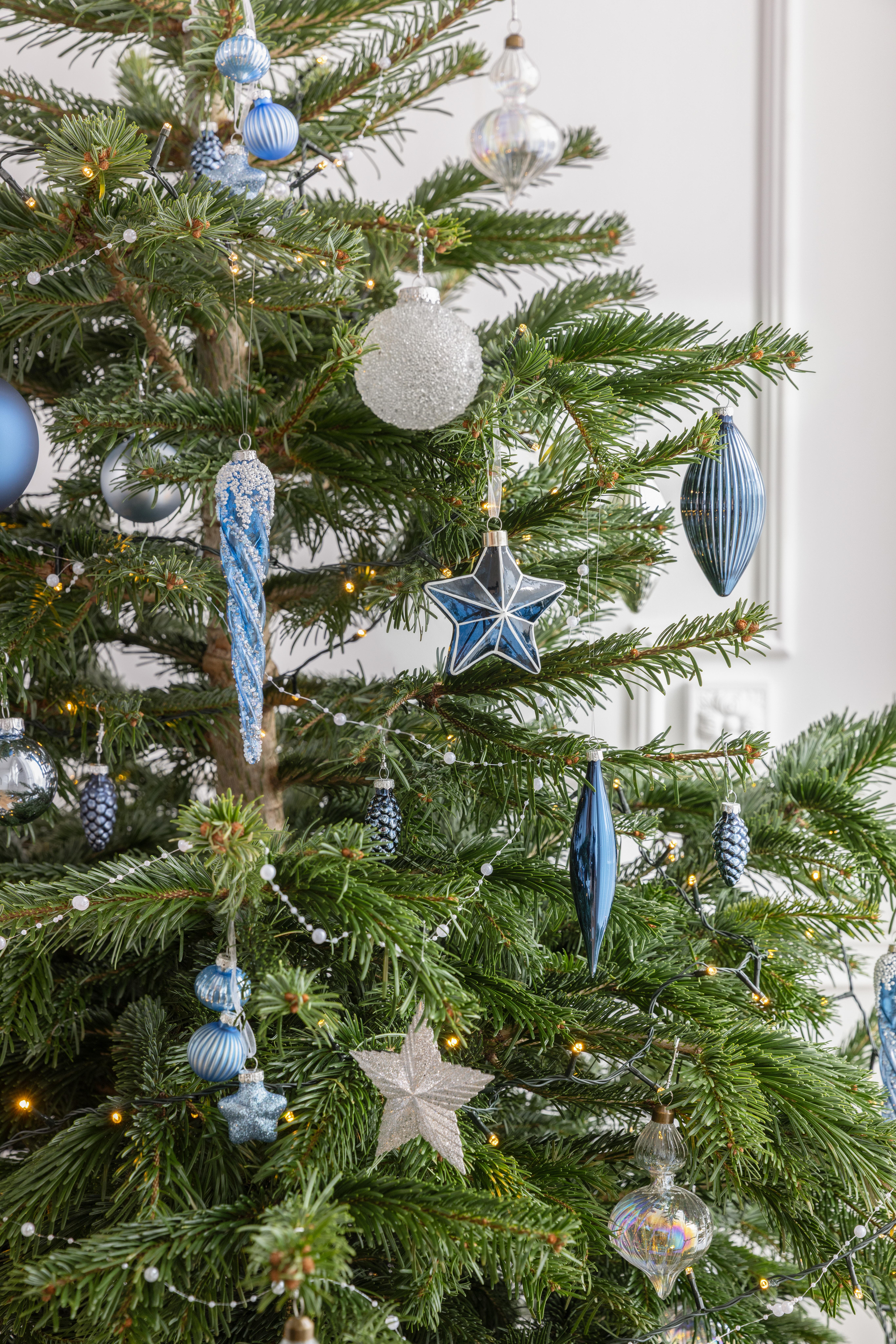 aranżacja, żywa choinka, która ma na gałązkach bombki w odcieniach niebieskiego i białego