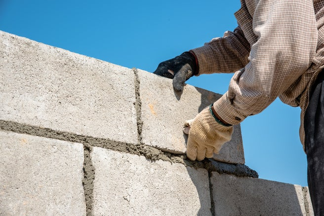 Fugowanie spoin między bloczkami betonowymi kielnia podczas murowania ściany fundamentowej.