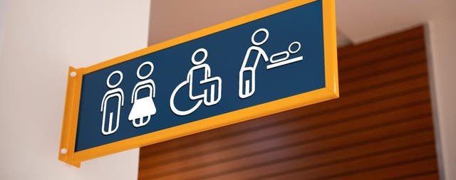 Tablica informacyjna wskazująca toaletę damską, męską, dla osób z niepełnosprawnościami oraz przewijak dla niemowląt.