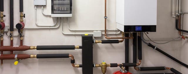 Instalacja kotła gazowego kondensacyjnego z miedzianymi rurami i rozdzielnią elektryczną w kotłowni.