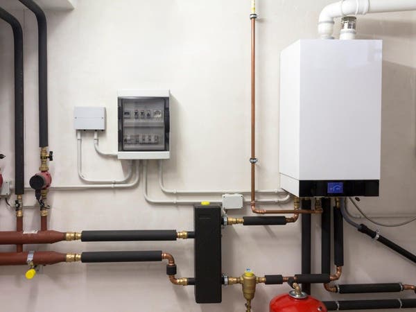 Instalacja kotła gazowego kondensacyjnego z miedzianymi rurami i rozdzielnią elektryczną w kotłowni.