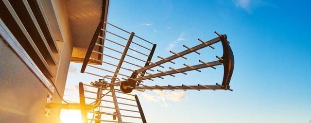 Antena dachowa do odbioru telewizji naziemnej zamontowana na elewacji budynku o zachodzie słońca.