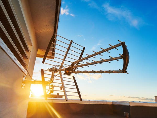 Antena dachowa do odbioru telewizji naziemnej zamontowana na elewacji budynku o zachodzie słońca.