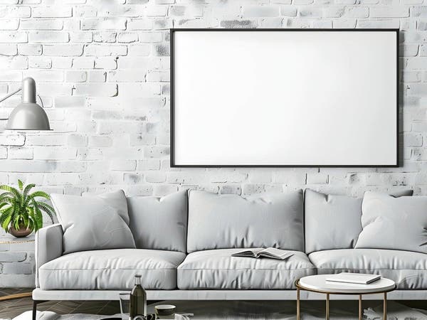 Nowoczesny salon w stylu loft z szarą sofą, roślinami dekoracyjnymi i pustą ramą na ścianie z malowanego kamienia dekoracyjnego.