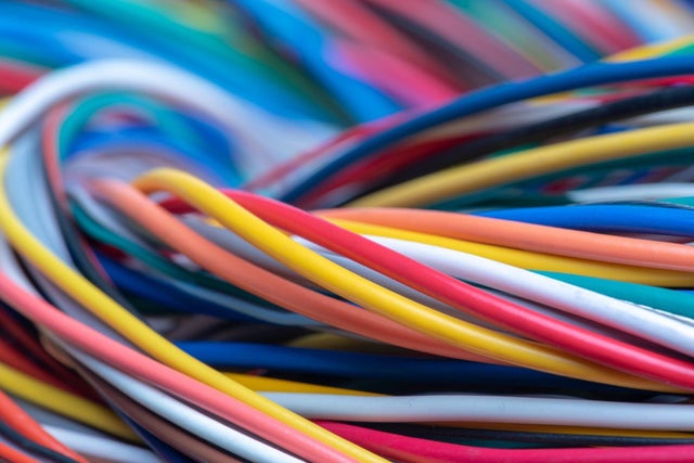 Zbliżenie na splątane kolorowe przewody elektryczne w różnych kolorach używane w instalacjach elektrycznych i telekomunikacyjnych.