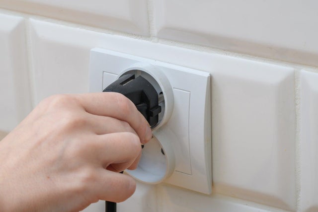 Dłoń wkładająca lub wyjmująca wtyczkę z gniazdka elektrycznego.