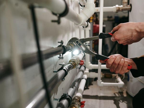 Dokręcanie połączenia rur instalacji hydraulicznej kluczem w pomieszczeniu technicznym.