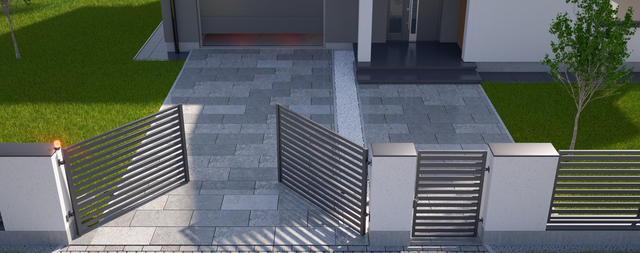 Podjazd z szarej kostki brukowej z aluminiową bramą dwuskrzydłową przy domu jednorodzinnym.