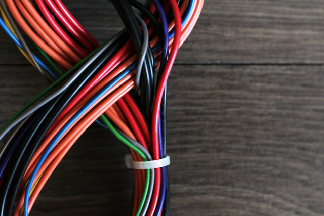 Kolorowe przewody elektryczne różnych kolorów spięte opaską kablową.