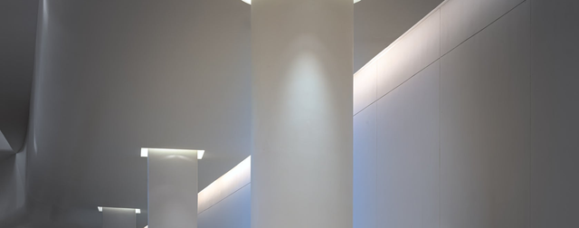 Nowoczesne białe kolumny architektoniczne z podświetleniem LED w suficie eleganckiego lobby budynku biurowego lub hotelowego.