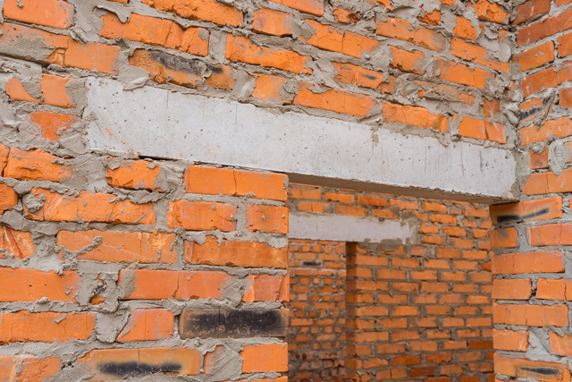 Betonowe nadproże okienne osadzone w murze z czerwonej cegły podczas budowy domu.