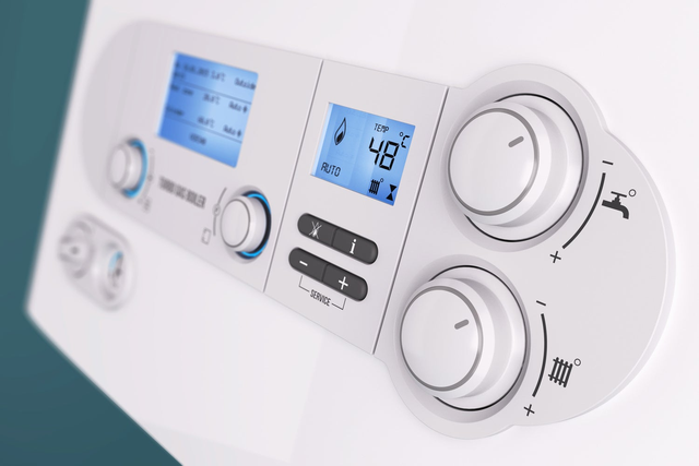 Zbliżenie na panel sterowania gazowego kotła grzewczego z wyświetlaczem LCD pokazującym temperaturę 48°C i pokrętłami regulacji.