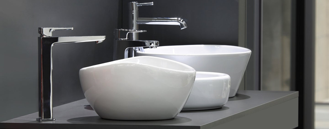 Ceramiczne umywalki na czarnym blacie w łazience pomalowanej na czarno.