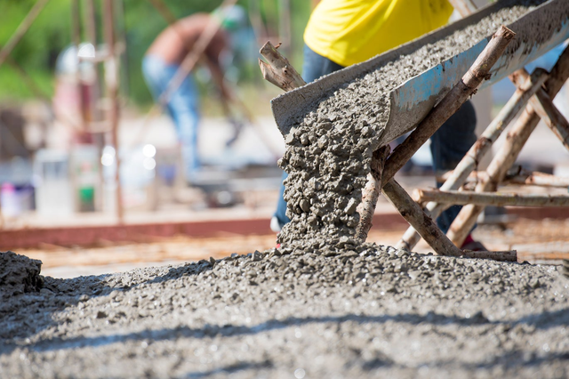 Cement wylewany z rynny na plac budowy podczas budowy fundamentu.