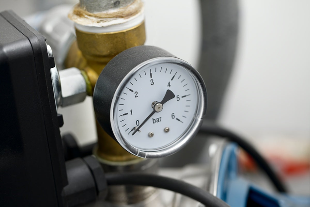 Okrągły manometr hydrauliczny z białą tarczą i czarną wskazówką pokazujący ciśnienie w instalacji.