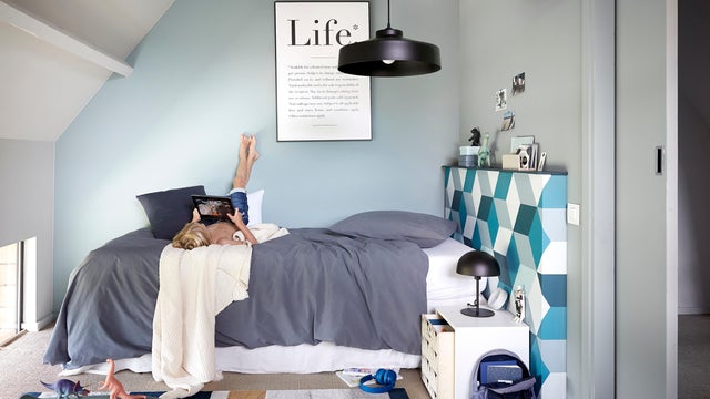 Dormitorio adolescente con el cabecero empapelado con papel geométrico. 