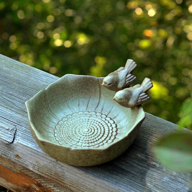 Okrągła ptasia kąpiel z dwoma dekoracyjnymi ceramicznymi ptakami. Nieporowata.